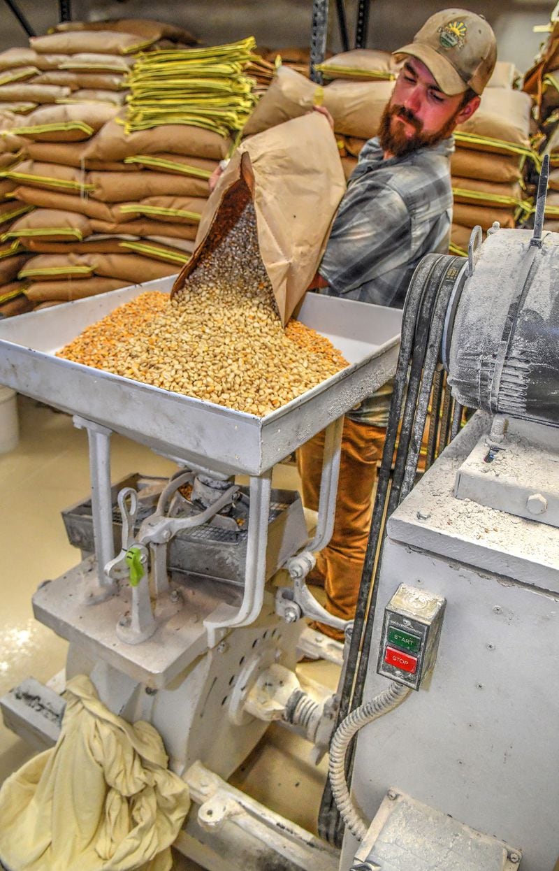 Nathan Brett, co-owner of DaySpring Farms in Danielsville, pours cleaned corn into a milling machine. DaySpring is an organic-certified farm that grows and mills wheat and corn on-site. Chris Hunt for The Atlanta Journal-Constitution
