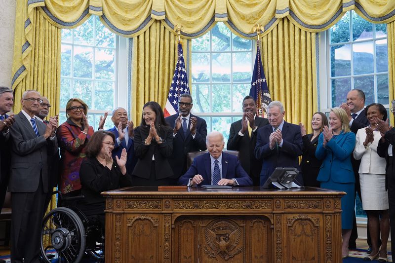 President Joe Biden, who is joined by civil rights leaders, community members, and elected officials, smiles after signing a proclamation in the Oval Office of the White House in Washington, Friday, Aug. 16, to designate the Springfield 1908 Race Riot National Monument. (AP Photo/Susan Walsh)