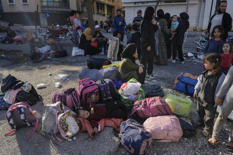 Families gather in Martyrs' square after fleeing the Israeli airstrikes in Beirut's southern suburbs, Saturday, Sept. 28, 2024. (AP Photo/Bilal Hussein)