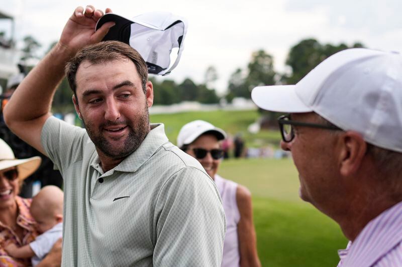 Scottie Scheffler, left, speaks with his father Scott Scheffler after Scottie's win in the final round of the Tour Championship golf tournament, Sunday, Sept. 1, 2024, in Atlanta. (AP Photo/Mike Stewart)