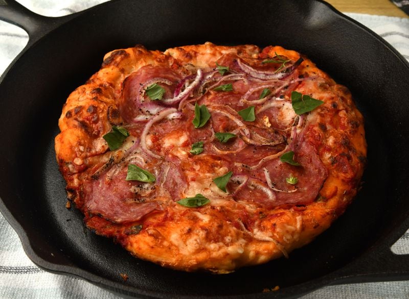 Crispy Skillet Pizza with Red Sauce, Salami, and Red Onion starts on the stovetop and finishes in the oven. (Styling by Susan Puckett / Chris Hunt for the AJC)