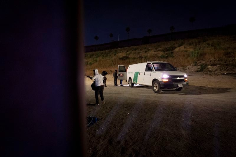 A migrant seeking asylum from Guatemala waves as he heads towards a Border Patrol vehicle to be processed, Tuesday, June 4, 2024, in San Diego. President Joe Biden on Tuesday unveiled plans to enact immediate significant restrictions on migrants seeking asylum at the U.S.-Mexico border as the White House tries to neutralize immigration as a political liability ahead of the November elections.(AP Photo/Gregory Bull)