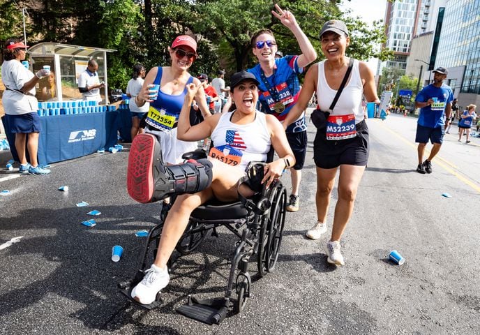 Jennifer Kenyon of Atlanta is pushed by her friends in a wheelchair up "Cardiac Hill" during the 55th running of The Atlanta Journal-Constitution Peachtree Road Race at "Cardiac Hill" on Peachtree Road NW in Atlanta on Thursday, July 4, 2024. (Seeger Gray / AJC)