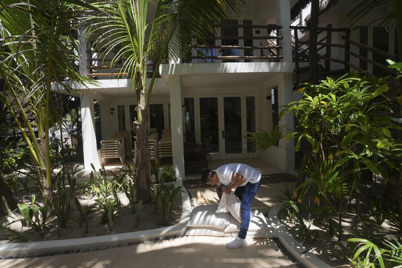 An employee places sandbags along a hotel path as protection from high waters in anticipation of Hurricane Beryl's arrival, in Tulum, Mexico, Thursday, July 4, 2024. (AP Photo/Fernando Llano)