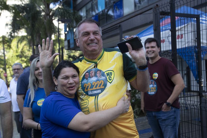 A supporter hugs former Brazilian President Jair Bolsonaro, center, as he campaigns for Rio de Janeiro mayoral candidate Alexandre Ramagem during the municipal elections in Rio de Janeiro, Sunday, Oct. 6, 2024. (AP Photo/Bruna Prado)