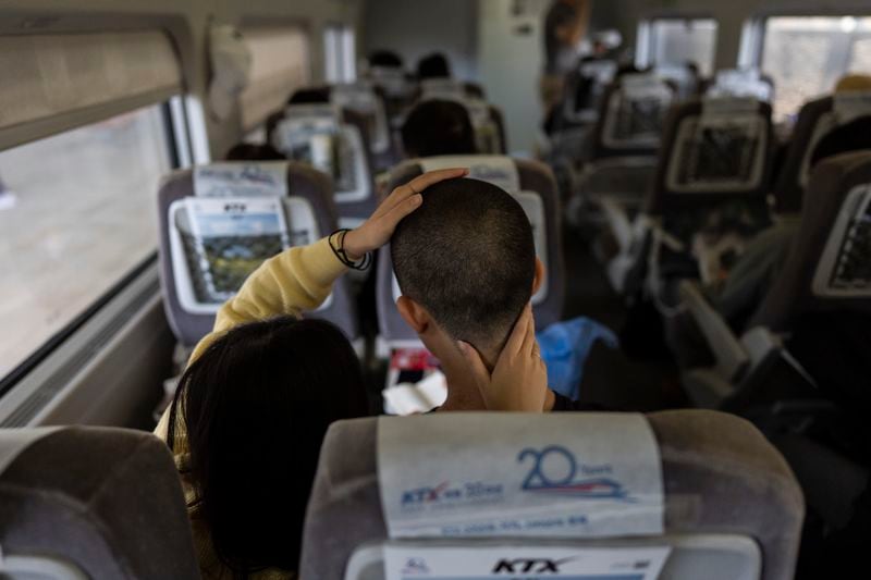 Kim Min-joo, left, feels the short haircut of her boyfriend, Kim Shin-hwa, on a train as they head to a Marine Corps induction ceremony in Pohang, South Korea, Monday, May 27, 2024. "As a South Korean man, I must enlist in military service at some point early in my life. No matter how frequently North Korea provokes or tensions rise, I cannot avoid my duty," said the recruit. (AP Photo/Jae C. Hong)