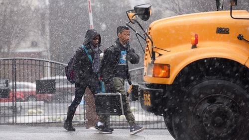 DeKalb County students board a bus as a wintry mix of snow, sleet and rain falls around them, Tuesday, Feb. 24, 2015, in Atlanta. The University of Georgia's Gwinnett campus delayed their opening while further west, the Cobb County school system canceled classes and weather forecasters predicted another round of winter weather for Wednesday. (AP Photo/David Tulis)