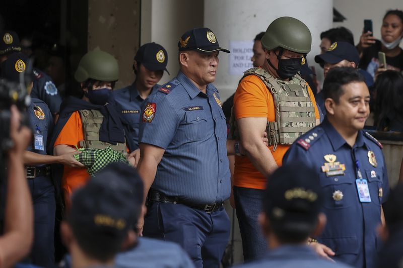 People, in green helmet, charged with human trafficking, leave the Pasig Regional Trial Court, walking after Apollo Carreon Quiboloy, a Filipino preacher, in Pasig City, Philippines, Friday, Sept. 13, 2024. (AP Photo/Gerard Carreon)