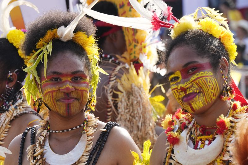 Women wear face paint and traditional headdress before Pope Francis gives an address during meeting with young people in the Sir John Guise Stadium in Port Moresby, Papua New Guinea, Monday, Sept. 9, 2024. (AP Photo/Mark Baker)