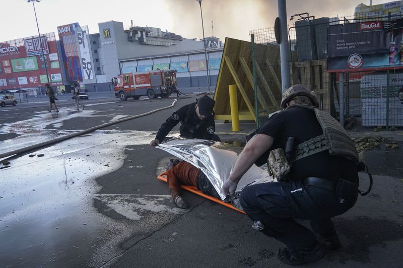 Police officers cover a dead body after two guided bombs hit a large construction supplies store in Kharkiv, Ukraine, Saturday, May 25, 2024. (AP Photo/Andrii Marienko)