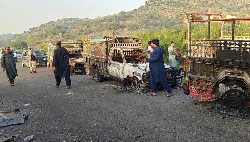 People look burnt vehicles, torched by gunmen after killing passengers, at a highway in Musakhail, a district in Baluchistan province in southwestern Pakistan, Monday, Aug. 26, 2024. (AP Photo/Rahmat Khan)