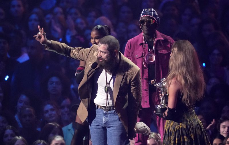 Post Malone, left, and Taylor Swift accept the award for best collaboration for "Fortnight"during the MTV Video Music Awards on Wednesday, Sept. 11, 2024, at UBS Arena in Elmont, N.Y. Jordan Chiles, back left, and Flava Flav look on.(Photo by Charles Sykes/Invision/AP)