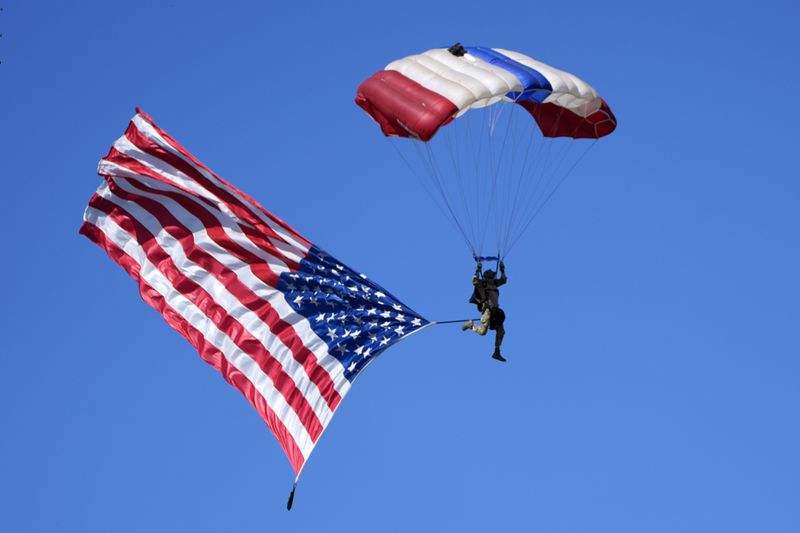 A parachuter with an American flag descends over a campaign event for Republican presidential nominee former President Donald Trump at the Butler Farm Show, Saturday, Oct. 5, 2024, in Butler, Pa. (AP Photo/Alex Brandon)