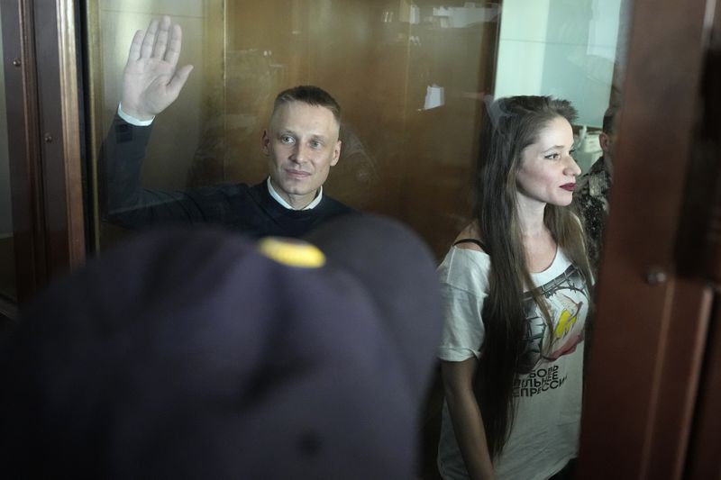 Russian journalists Konstantin Gabov, left, and Antonina Favorskaya, accused of working for a group founded by the late Russian opposition politician Alexei Navalny, stand in a defendant's cage of the Nagatinsky District Court in Moscow, Russia, on Wednesday, Oct. 2, 2024. (AP Photo)