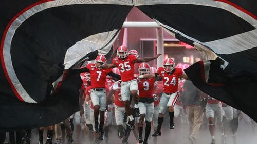 Georgia players break through the giant banner while taking the field.    Curtis Compton/ccompton@ajc.com