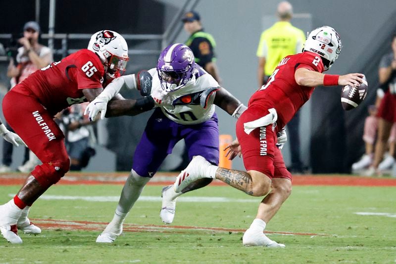 North Carolina State quarterback Grayson McCall (2) struggles to break away from Western Carolina's Edwin Moore Jr. (50) as NC State's Jacarrius Peak (65) defends during the second half of an NCAA college football game in Raleigh, N.C., Thursday, Aug. 29, 2024. (AP Photo/Karl B DeBlaker)