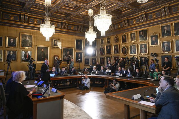 FILE - Mats Larsson, member of the Royal Academy of Sciences, standing at left, speaks during the announcement of the winner of the 2023 Nobel Prize in Physics, at the Royal Academy of Sciences, in Stockholm, on Oct. 3, 2023. (Anders Wiklund/TT News Agency via AP, File)