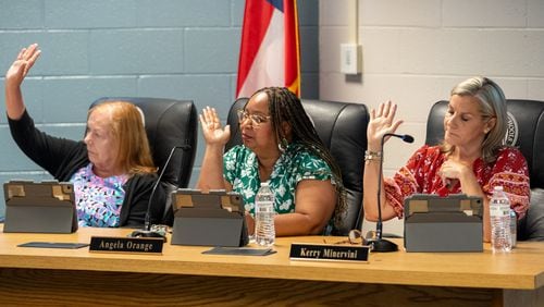 Marietta school board members raise their hand in support of a staff proposal to limit cellphone use by middle school students during its meeting on June 18, 2024. (Ben Hendren for the Atlanta Journal-Constitution)