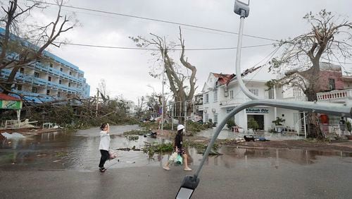 People walk past broken light post after typhoon Yagi hit the city, in Hai Phong, northern Vietnam on Sunday, Sept. 8, 2024. (Minh Quyet/VNA via AP)