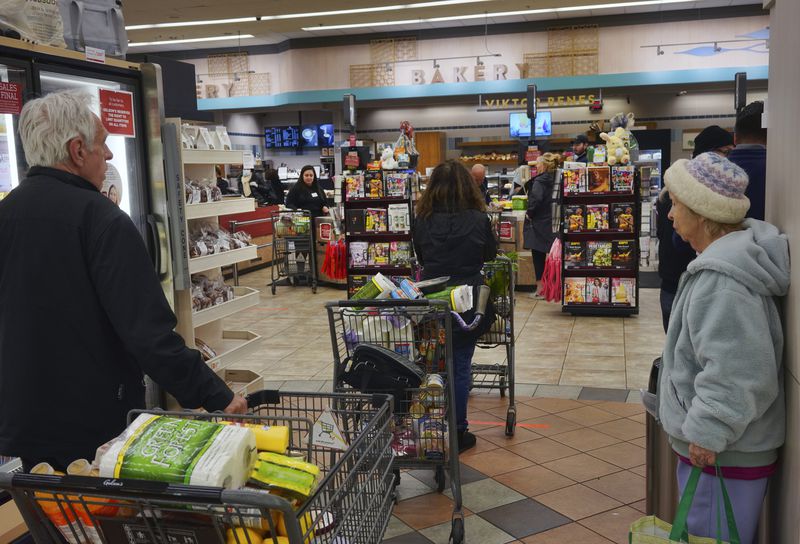 FILE - Shoppers wait in line to buy groceries at a Gelson's supermarket Friday, March 20, 2020, in the Sherman Oaks section of Los Angeles. (AP Photo/Richard Vogel, File)