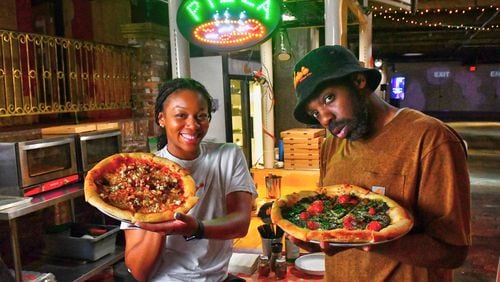 Dolo’s Pizza pop-up in Underground Atlanta, with owners Alyson Williams (left) and Yusef Walker showing off two of their pizzas. (CHRIS HUNT FOR THE ATLANTA JOURNAL-CONSTITUTION)