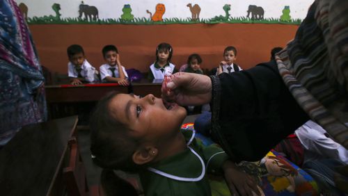 A health worker administers a polio vaccine to a child at a school in Peshawar, Pakistan, Monday, Sept. 9, 2024. (AP Photo/Muhammad Sajjad)