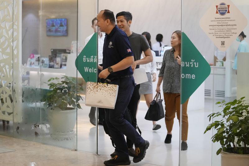 A staff member, left, from British Embassy arrives at Samitivej Hospital in Bangkok, Thailand, Wednesday, May 22, 2024. A Singapore Airlines flight hit severe turbulence over the Indian Ocean and descended 6,000 feet (around 1,800 meters) in about three minutes, the carrier said Tuesday. A British man died and authorities said dozens of passengers were injured, some severely. (AP Photo/Sakchai Lalit)