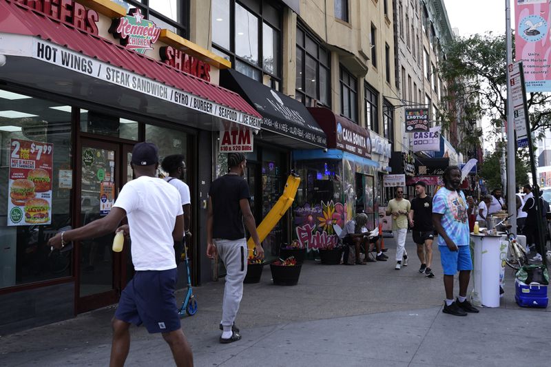 People walk through the Harlem neighborhood of New York, Thursday, Aug. 15, 2024. (AP Photo/Pamela Smith)