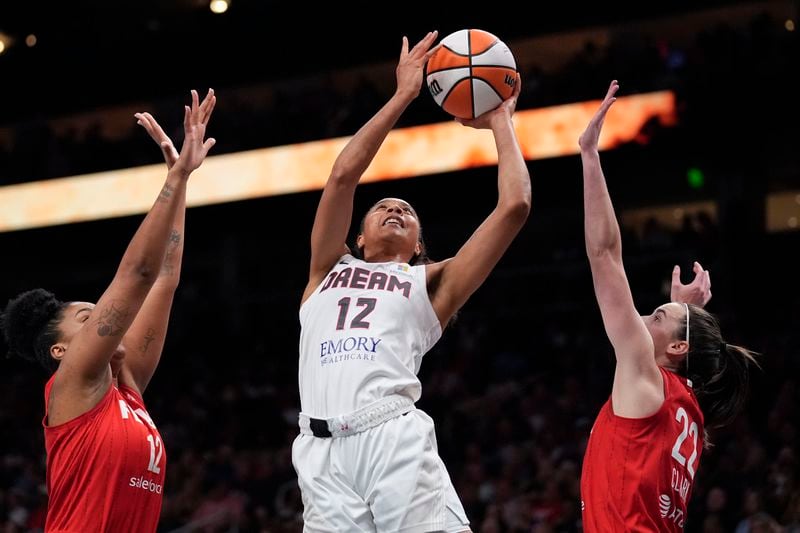 Atlanta Dream's Nia Coffey (12) shoots against Indiana Fever's Caitlin Clark (22) and Damiris Dantas (12) in the second half of an WNBA basketball game Monday, Aug. 26, 2024, in Atlanta. (AP Photo/Brynn Anderson)