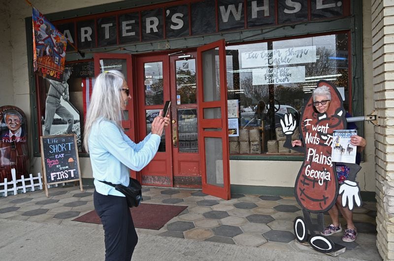 Donna Peardon (left), of Spring Hill, Florida, takes a picture of her friend Cathy Carroll of Calhan, Colorado, as she holds a Colorado magazine in front of Bobby Salter's Plain Peanuts and General Store, Thursday, Feb. 23, 2023, in Plains, GA. Donna Peardon and Cathy Carroll decided come to Plains after they heard President Jimmy Carter entered home hospice care. (Hyosub Shin / Hyosub.Shin@ajc.com)