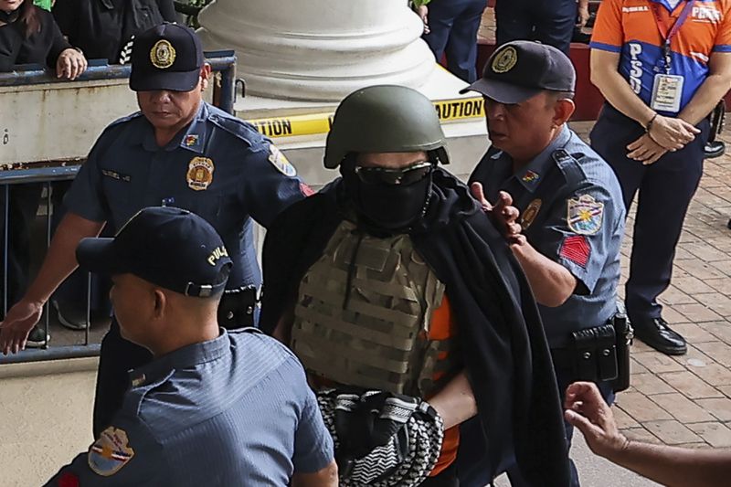 Apollo Carreon Quiboloy, wearing a helmet and flak jacket, a Filipino preacher charged with human trafficking, enters the Pasig Regional Trial Court in Pasig City, Philippines, Friday, Sept. 13, 2024. (AP Photo/Gerard Carreon)