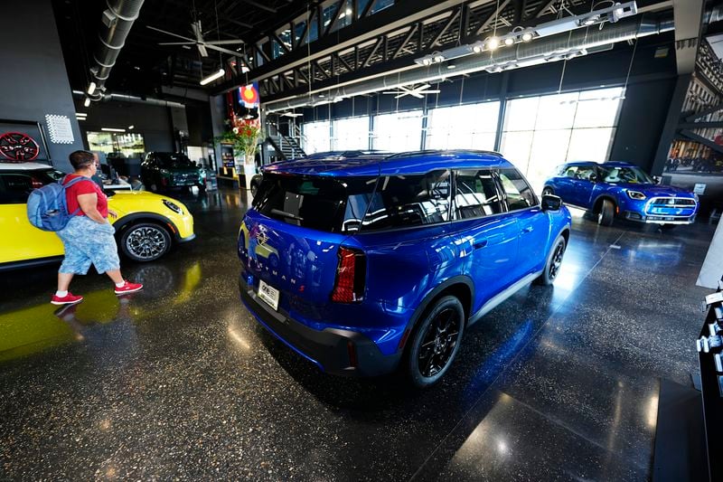 A shopper looks over an unsold 2025 Cooper S hardtop on display with Countryman S utility vehicles in the showroom of a Mini dealership Wednesday, Sept. 4, 2024, in Highlands Ranch, Colo. (AP Photo/David Zalubowski)