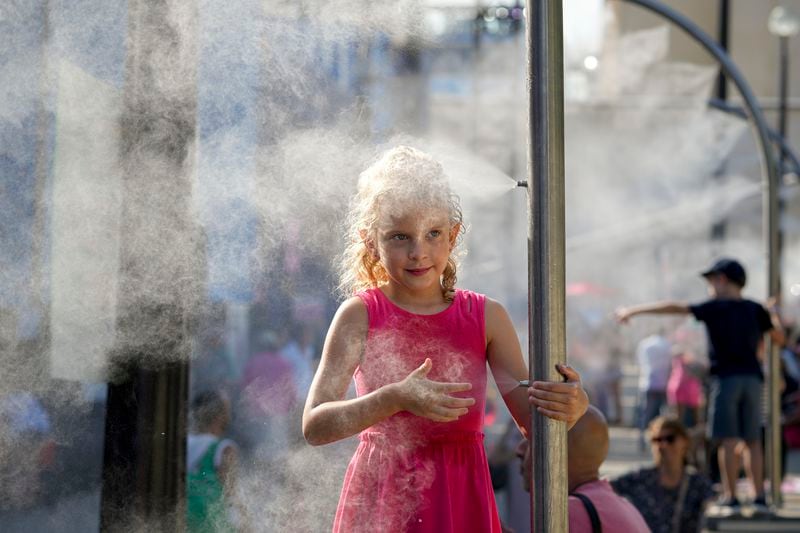 FILE - Anna, 7, cools off under a misting fountain on a hot afternoon during the 2024 Summer Olympics, Monday, July 29, 2024, in Paris, France. (AP Photo/Vadim Ghirda, File)