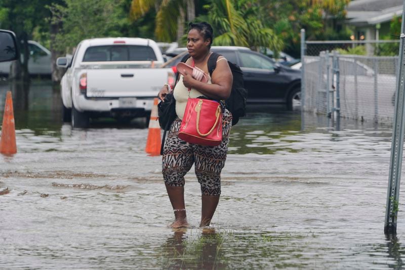 A woman walks with her belongings on a flooded street, Thursday, June 13, 2024, in North Miami, Fla. Over 20 inches of rain fell over two days was in North Miami. A tropical disturbance has brought a rare flash flood emergency to much of southern Florida. Floridians prepared to weather more heavy rainfall on Thursday and Friday. (AP Photo/Marta Lavandier)