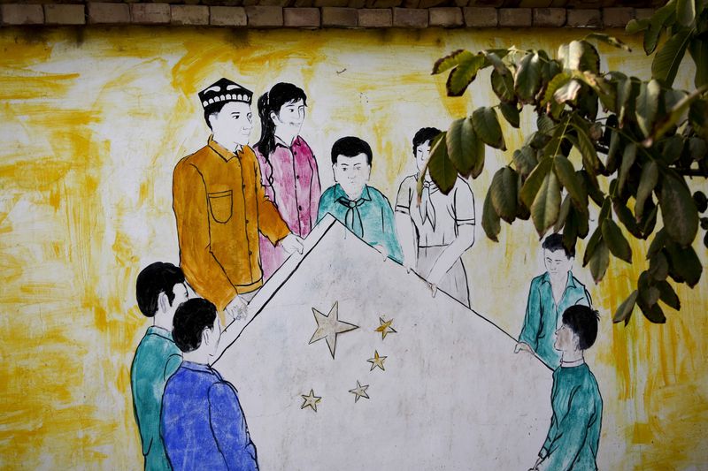 FILE - A mural showing Uighur and Han Chinese men and women carrying the national flag of China decorates the wall of a home at the Unity New Village in Hotan, in western China's Xinjiang region on Sept. 20, 2018. Authorities in China's western Xinjiang region have been systematically replacing the names of villages inhabited by Uyghurs and other ethnic minorities to reflect the ruling Communist Party's ideology, as part of an attack on their cultural identity, according to a report released Wednesday, June 19, 2024, by Human Rights Watch. (AP Photo/Andy Wong, File)