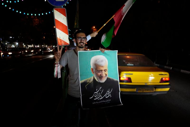 A supporter of Saeed Jalili, a candidate for the presidential election, holds his poster as he flashes a victory sign during a campaign gathering in Tehran, Iran, Wednesday, June 26, 2024. (AP Photo/Vahid Salemi)
