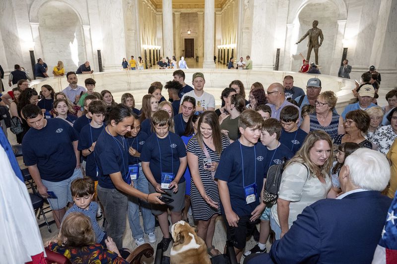 This photo provided by the West Virginia Legislature shows crowds as they greet West Virginia Gov. Jim Justice's English Bulldog, Babydog, center, at the unveiling of four new murals depicting the state's culture and history at the West Virginia Capitol in Charleston, W.Va., Thursday, June 20, 2024. (Perry Bennett/West Virginia Legislature via AP)