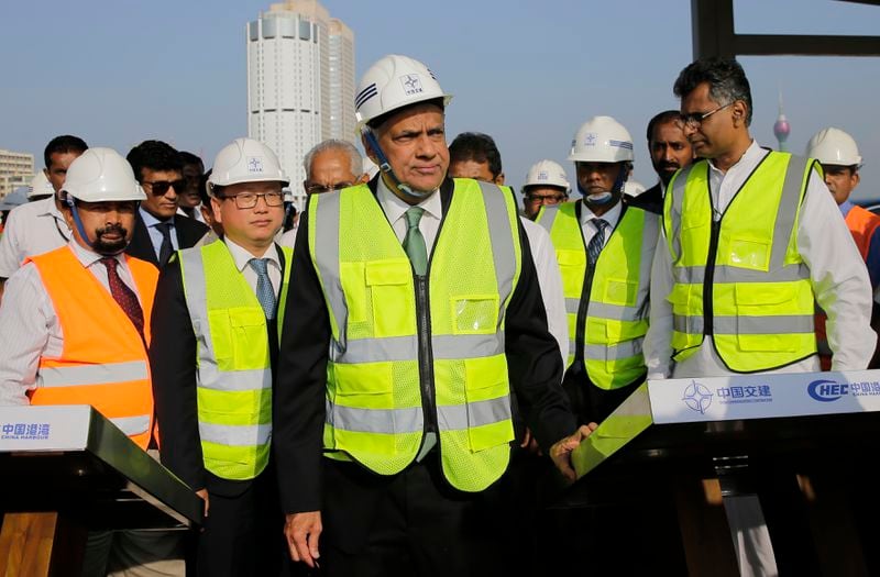 FILE - Then Sri Lankan Prime Minister Ranil Wickremesinghe, center, watches the land that was reclaimed from the Indian Ocean for the Colombo Port City project, part of China's One Belt One Road Initiative, on the Galle Face sea promenade in Colombo, Sri Lanka, on Jan. 2, 2018. (AP Photo/Eranga Jayawardena, File)