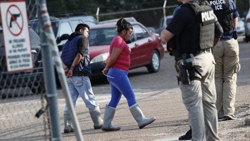 Two people are taken into custody at a Koch Foods Inc. plant in Morton, Miss., on Wednesday, Aug. 7, 2019. U.S. immigration officials raided several Mississippi food processing plants on Wednesday and signaled that the early-morning strikes were part of a large-scale operation targeting owners as well as employees. (AP Photo/Rogelio V. Solis)