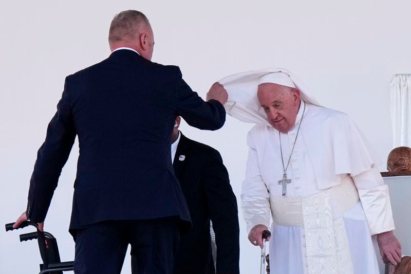 An aide assists Pope Francis with his cape after he gave an address during meeting with young people in the Sir John Guise Stadium in Port Moresby, Papua New Guinea, Monday, Sept. 9, 2024. (AP Photo/Mark Baker)