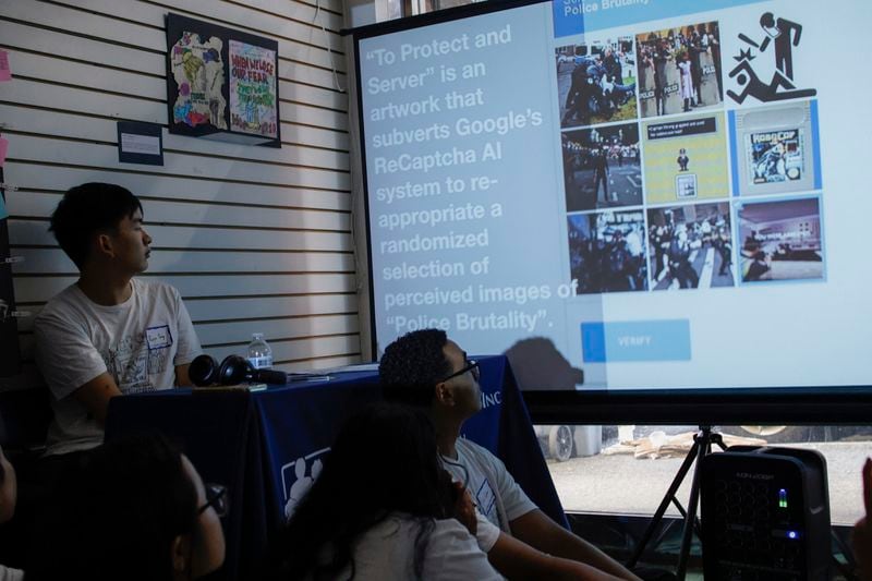 Students looks at images created by artist Jonah Brucker-Cohen during the opening of an art contest titled "Hacked the Hate" made by young artists, Thursday, Aug. 8, 2024, in New York. (AP Photo/Kena Betancur)