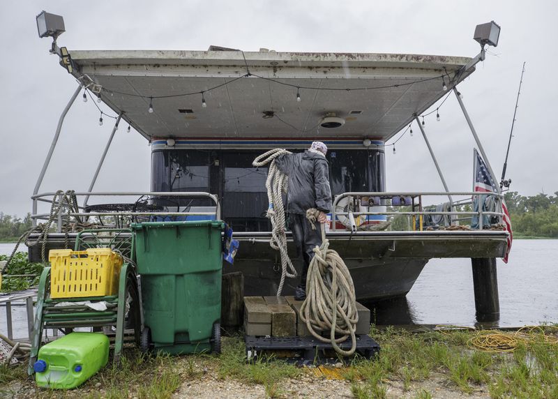 Jason Bledsoe hauls rope to a houseboat in preparation of moving it to a safer dock, Wednesday, Sept. 11, 2024, in Bayou Gauche, La., ahead of Hurricane Francine. (David Grunfeld/The Times-Picayune/The New Orleans Advocate via AP)