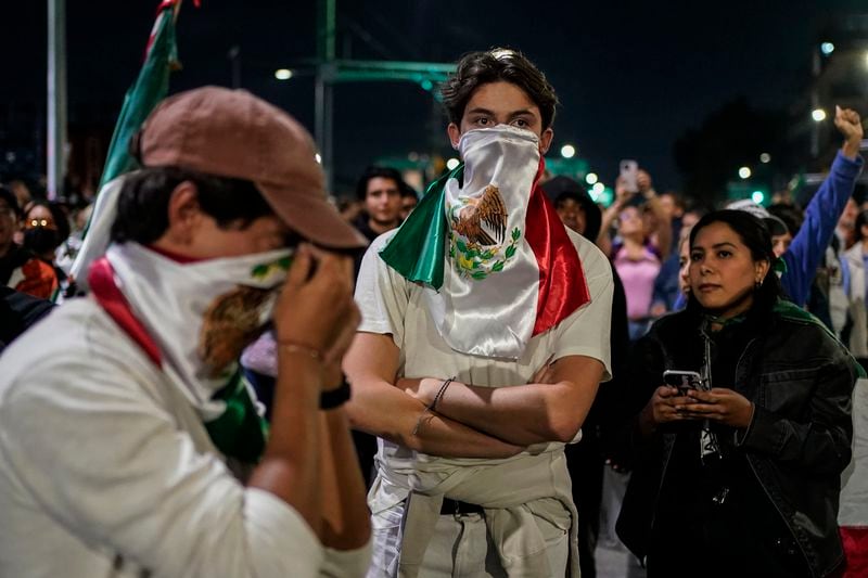 Two students cover their faces with the Mexican flag during a protest against government's proposed judicial reform, which would make judges stand for election, outside the Senate in Mexico City, Tuesday, Sept. 10, 2024. (AP Photo/Felix Marquez)