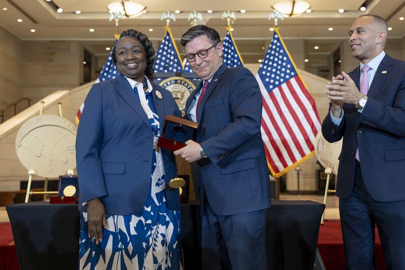 House Speaker Mike Johnson, R-La., accidentally drops a Congressional Gold Medal while posing for a photograph with NASA's Johnson Space Center Senior Apollo Sample Processor and Lab Manager Andrea Mosie, left, at a Congressional Gold Medal ceremony to honor the Black women mathematicians of NASA who contributed to the space race and who were the subject of the book and movie "Hidden Figures," at the Capitol in Washington, Wednesday, Sept. 18, 2024. House Minority Leader Hakeem Jeffries, D-N.Y., watches at right. (AP Photo/J. Scott Applewhite)