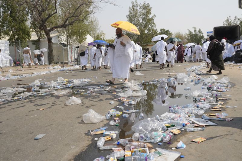 Muslim pilgrims walk a street littered with thrashed water bottle in Arafat, on the second day of the annual hajj pilgrimage, near the holy city of Mecca, Saudi Arabia, Saturday, June 15, 2024. (AP Photo/Rafiq Maqbool)