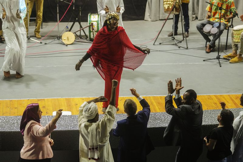 Sudanese Camirata troupe dancer Hoda Othman, performs a dance from Central Sudan, "Al-Arda", as Sudanese and foreign audience react during a show at the Russian culture center in Cairo, Egypt, Sunday, Sept. 15, 2024. (AP Photo/Amr Nabil)