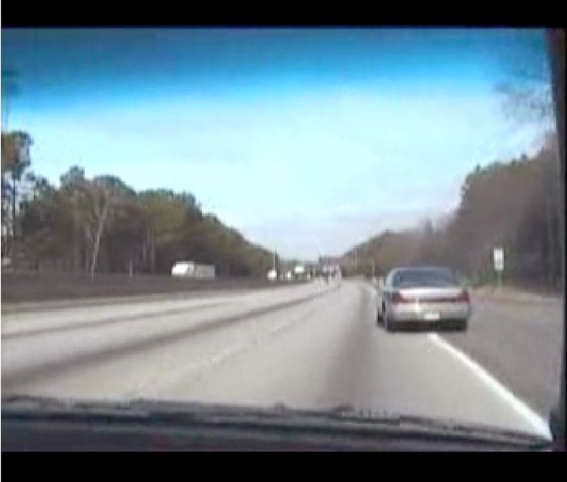 A car passes the group in the emergency lane of I-285; this is a screen grab from "A Meditation On the Speed Limit"/AJC file