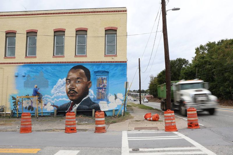 Cars drive by as Kevin “Scene” Lewis works on a mural of Rev. Martin Luther King Jr. on Wednesday, Sept. 11, 2024, off of Martin Luther King Jr. Boulevard in Macon, Georgia. The mural will depict King as well as cherry blossoms and Zion Baptist Church, the last place King visited in Macon before his assassination in 1968. (Photo Courtesy of Katie Tucker/The Telegraph)