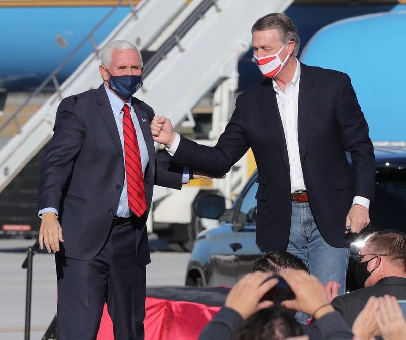 U.S. Sen. David Perdue, left, gives Vice President Mike Pence a thank-you bump on the chest at the conclusion of the "Defend the Majority" rally Thursday in Augusta. Curtis Compton / Curtis.Compton@ajc.com