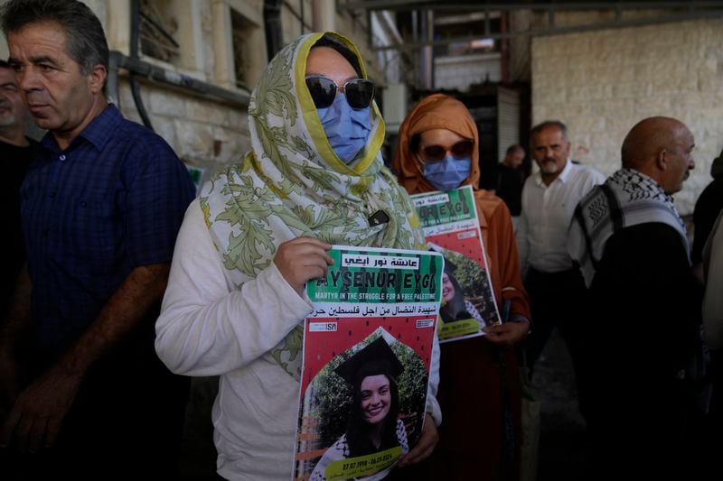 Two fellow activists of Aysenur Ezgi Eygi, 26, who was fatally shot by Israeli soldiers while participating in an anti-settlement protest in the West Bank, carry posters with her name and photo during Eygi's funeral procession in the West Bank city of Nablus, Monday, Sept. 9, 2024. (AP Photo/Nasser Nasser)